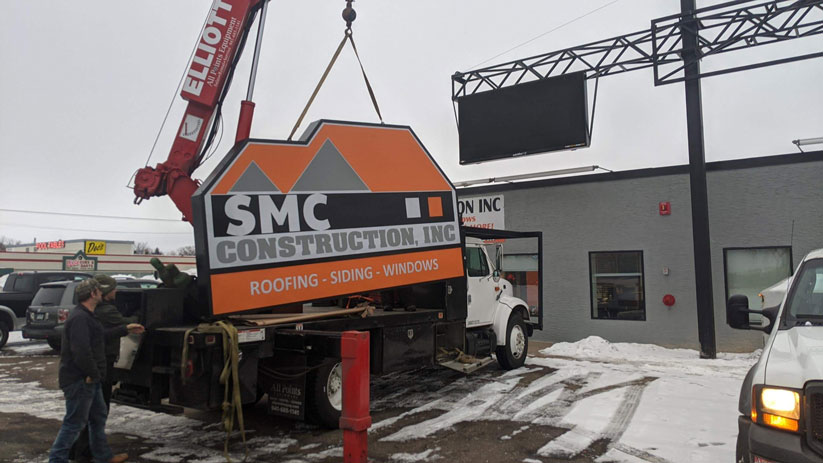 SMC Construction, Inc Sign being moved by a crane